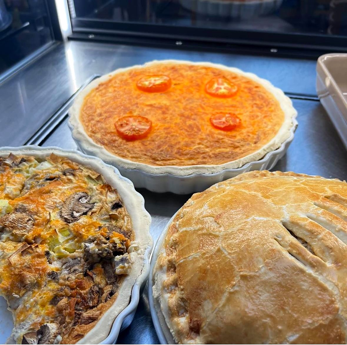 Baked quiches and a pie in their dishes